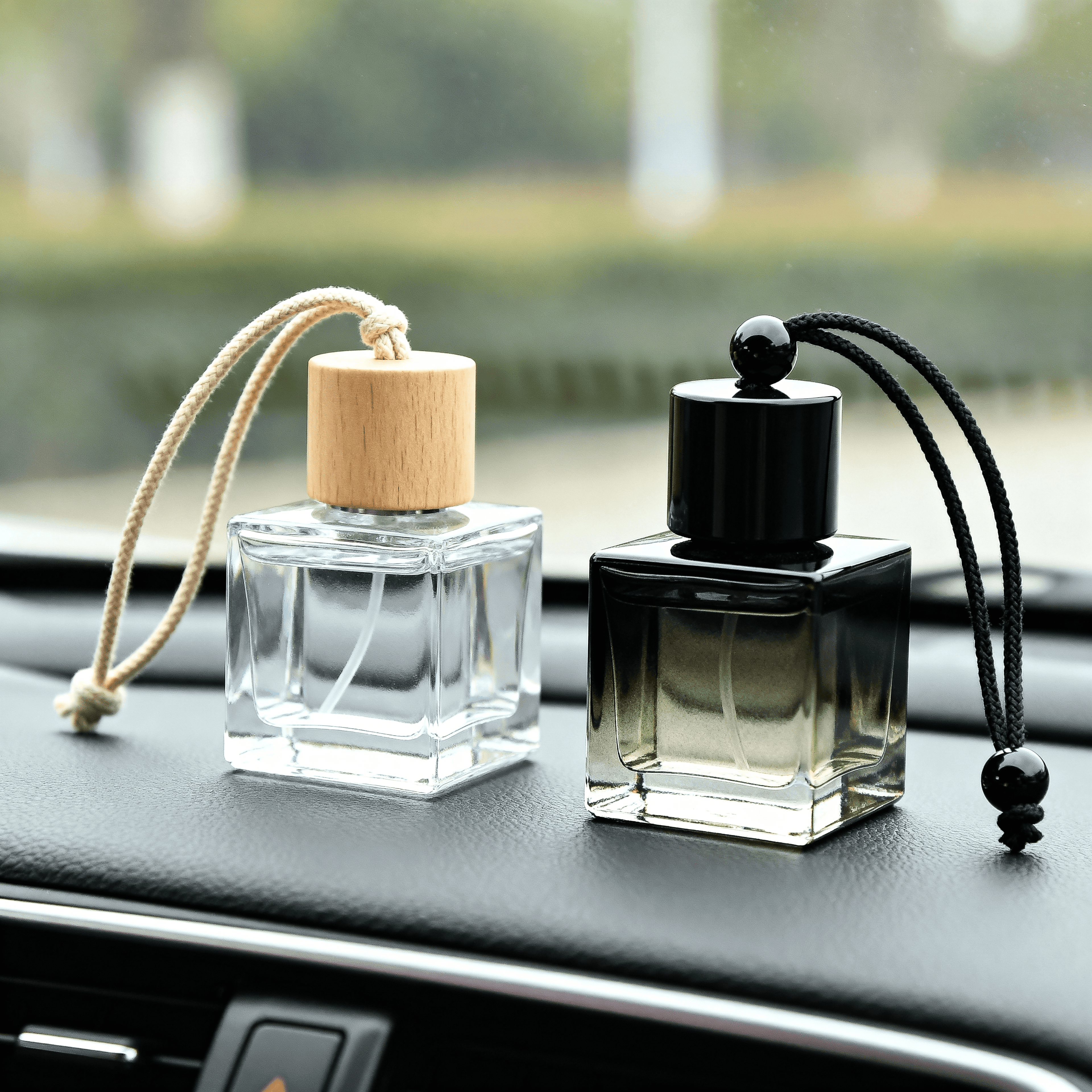 Two car air fresheners on a car dashboard with blurred greenery in the background.